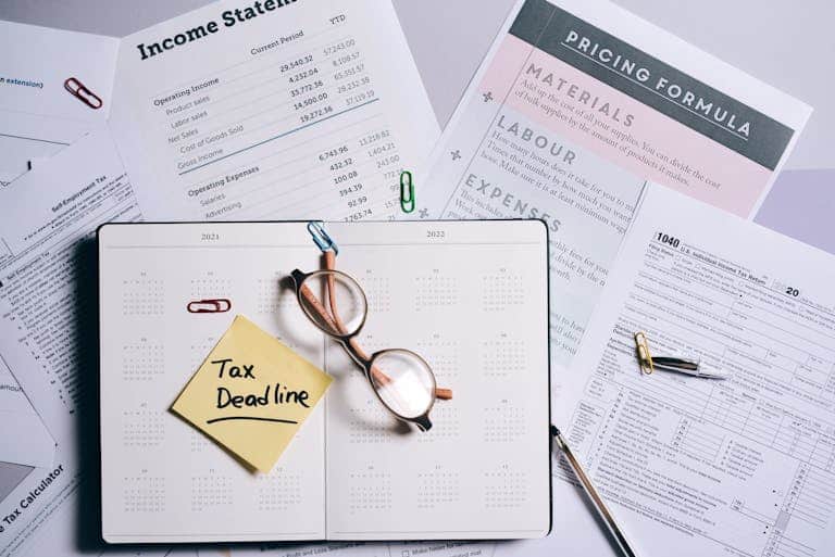 Overhead view of financial documents, planner, and glasses emphasizing tax deadline.